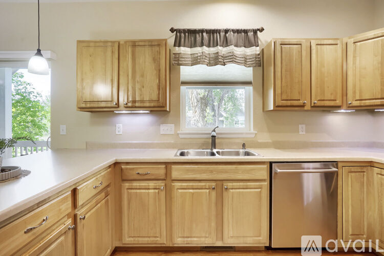 A kitchen with wooden cabinets and a stainless steel dishwasher.