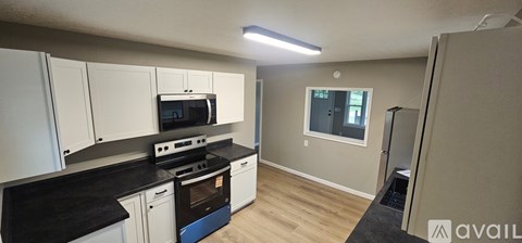 A kitchen with white cabinets and black countertops.