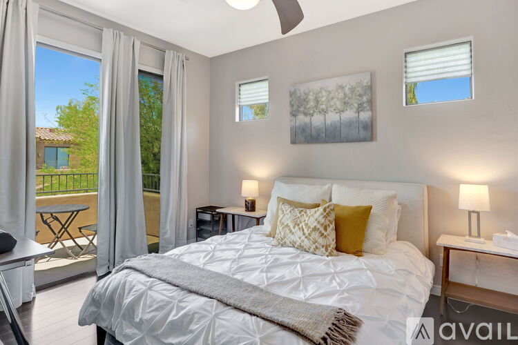 A bedroom with a large bed and a view of a patio with a table and chairs.