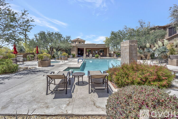 A pool area with a table and chairs and a building in the background.
