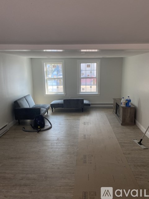 A living room with a grey sofa and a black vacuum cleaner.