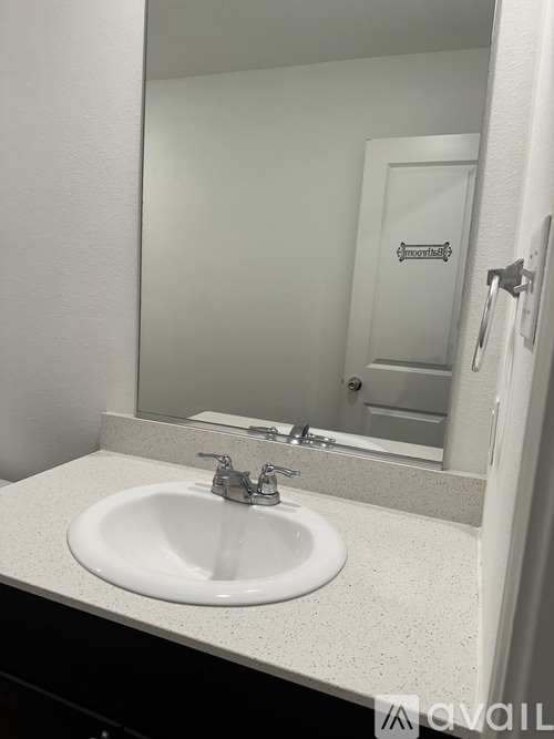 A white sink is in front of a mirror in a bathroom.