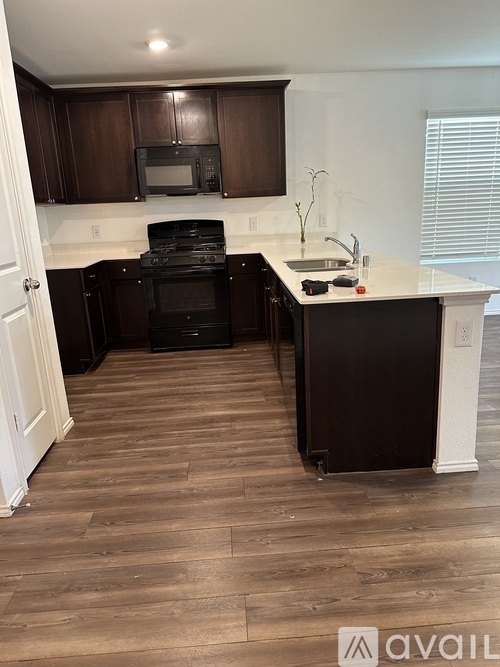 A kitchen with dark brown cabinets and a black oven.