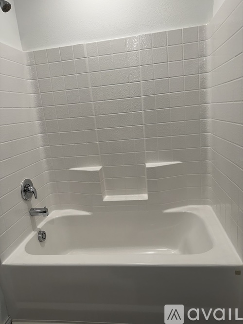 A white bathtub with a shower head and faucet.