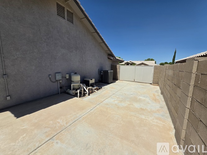 A concrete backyard with a wall and a building in the background.