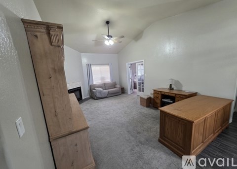 A living room with a grey carpet and a wooden cabinet.