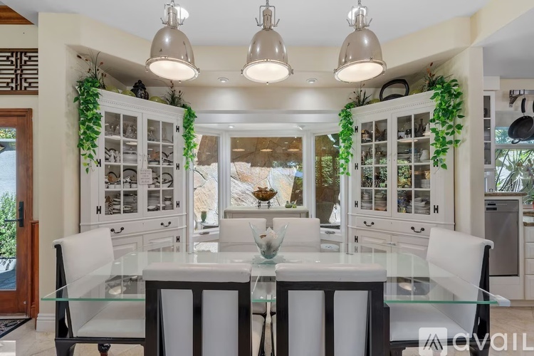 A modern dining room with a glass table and white chairs.