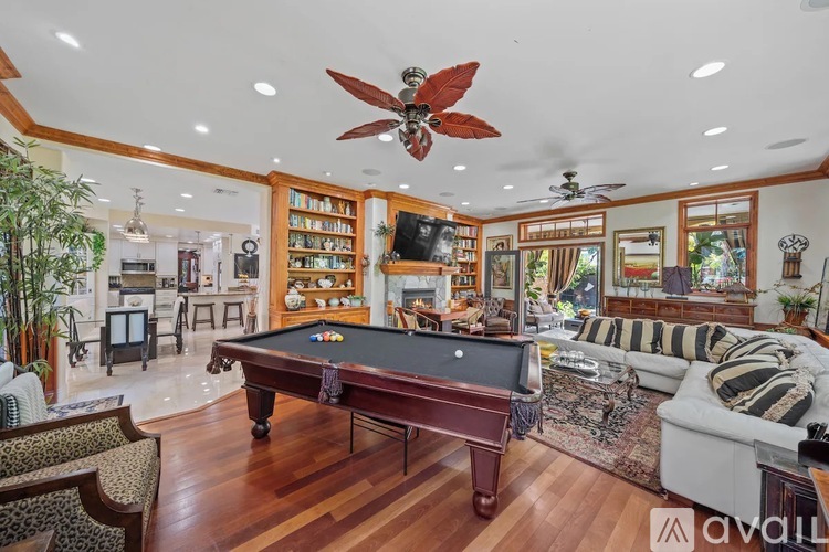 A pool table is in the middle of a room with a ceiling fan.