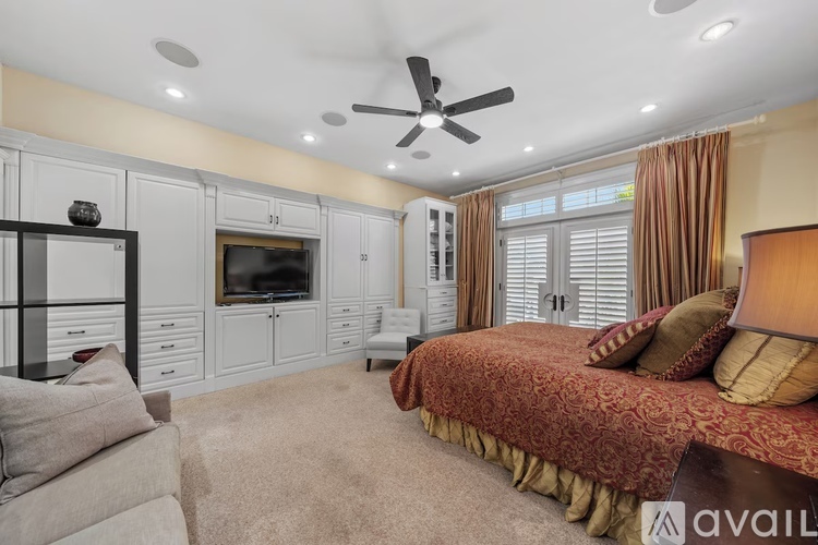 A bedroom with a bed, a couch, and a television in a cabinet.