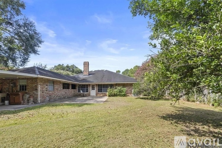A house with a chimney is surrounded by a grassy yard.