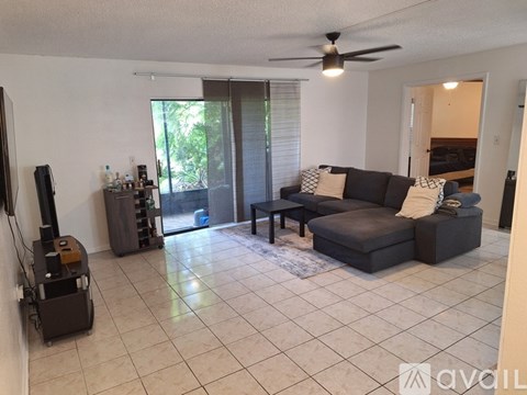 A living room with a black couch and a ceiling fan.