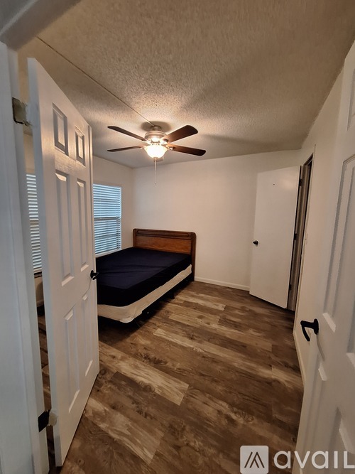 A bedroom with a bed, a ceiling fan, and a door.