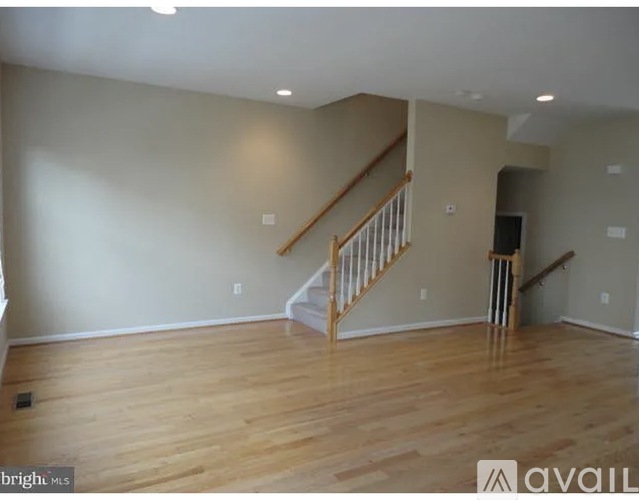 A spacious room with wooden floors and a staircase.