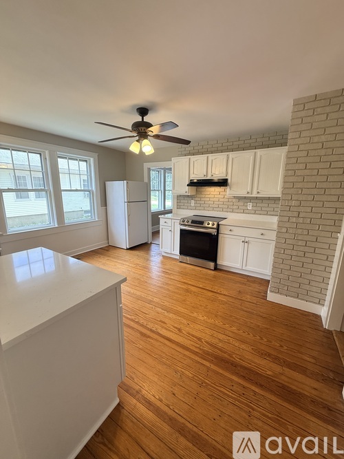 A kitchen with a white countertop and wooden floors.