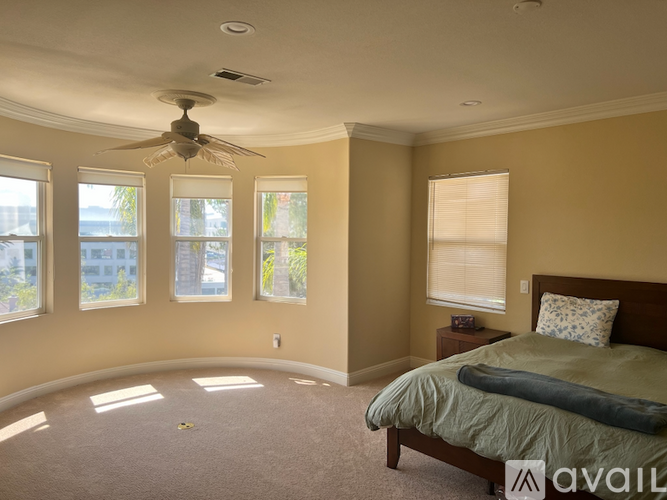 A bedroom with a bed, a fan, and a window.