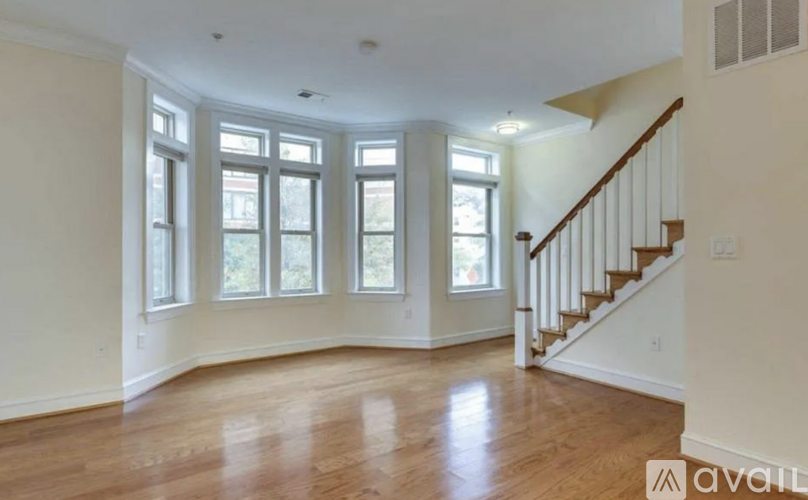 A spacious room with wooden floors and a staircase leading to another level.
