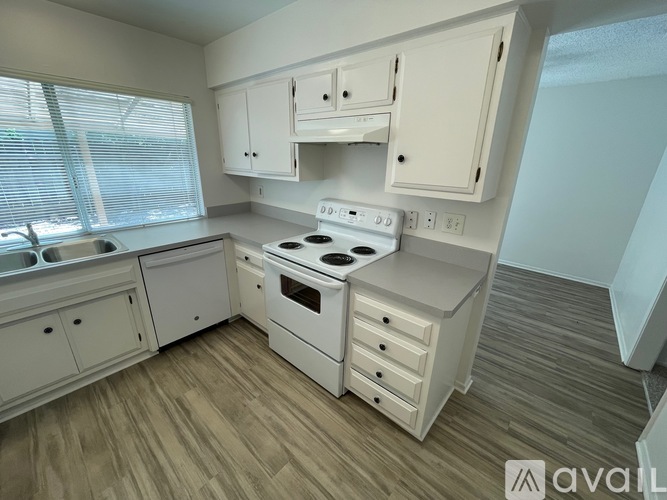 A kitchen with a white stove top oven and white cabinets.