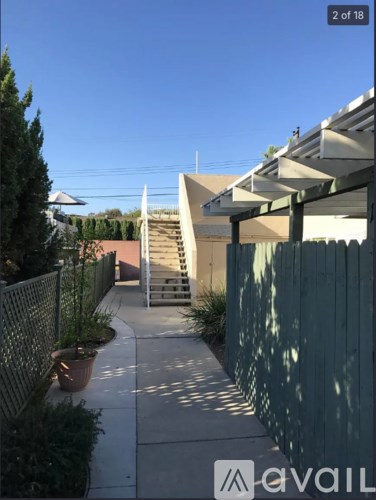 A sidewalk with a metal fence and a building in the background.