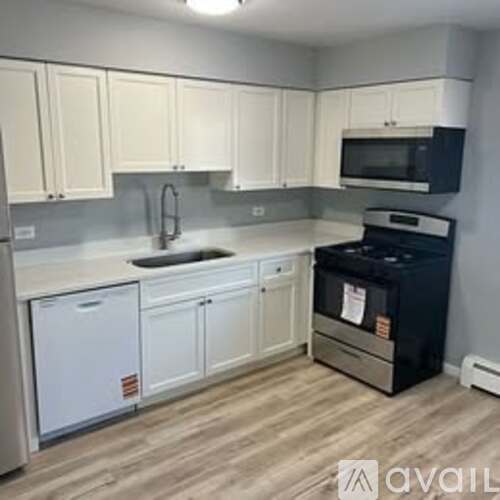 A kitchen with white cabinets and a black dishwasher.