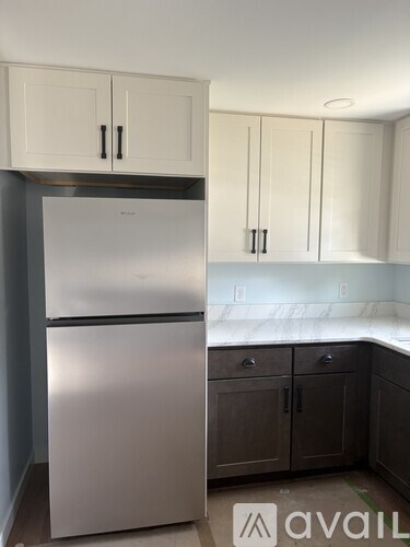 A kitchen with a refrigerator, cabinets, and a countertop.