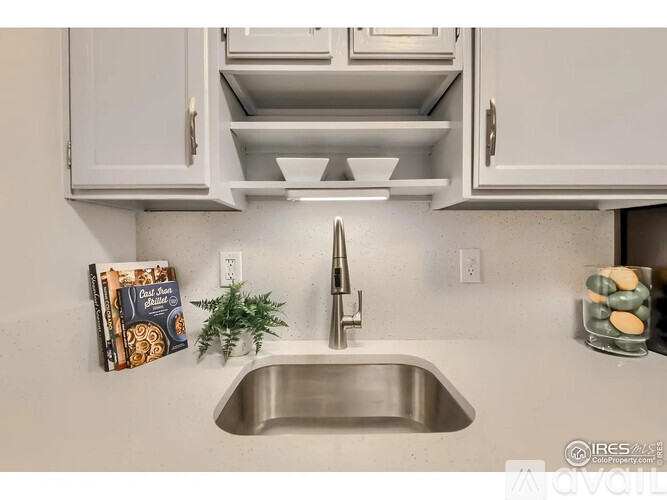 A kitchen with a stainless steel sink and white cabinets.
