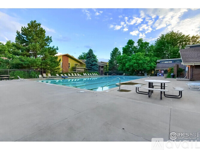 A swimming pool surrounded by trees and a picnic table.