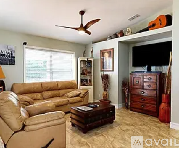 A living room with a brown couch and a ceiling fan.
