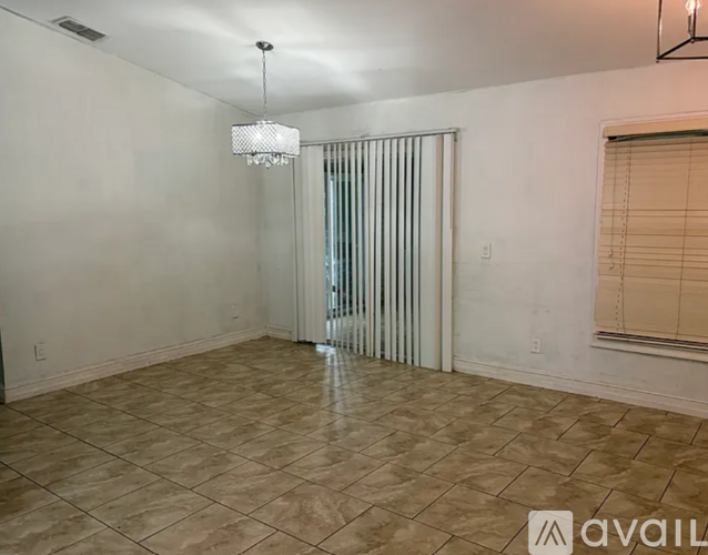 A room with a chandelier, tiled floor, and a window with blinds.