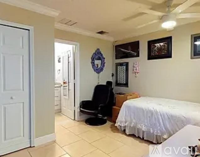 A bedroom with a bed, chair, and a wreath on the wall.