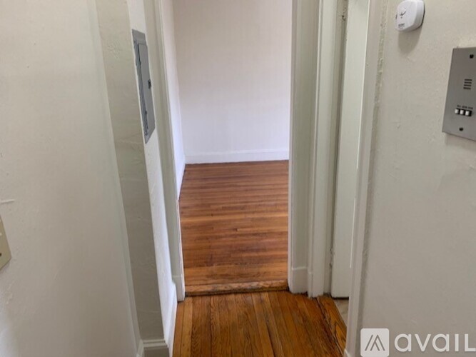 A hallway with a wooden floor and white walls.