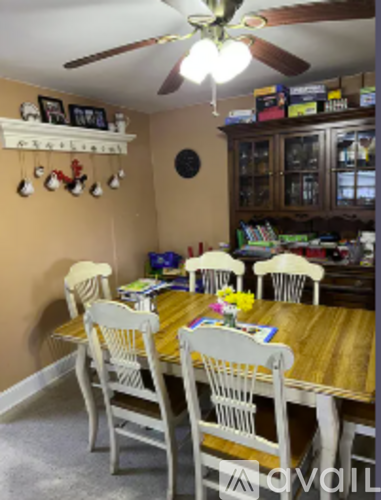 A dining room with a wooden table and white chairs.