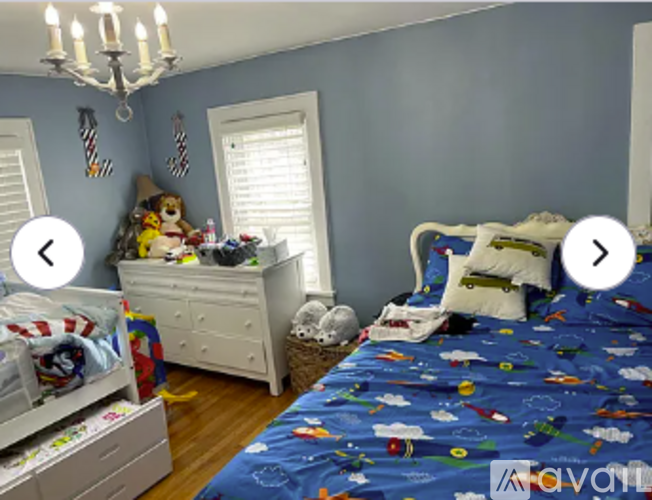 A bedroom with a blue bedspread and a white dresser.