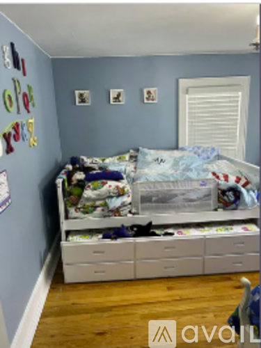 A child's bedroom with a white bed and drawers.