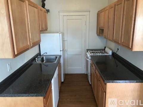 A kitchen with wooden cabinets and black countertops.