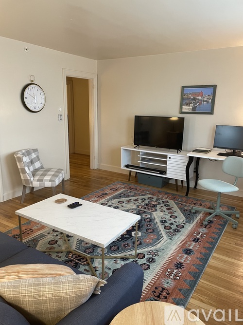 A living room with a white sofa and a white coffee table with a rug on the floor.