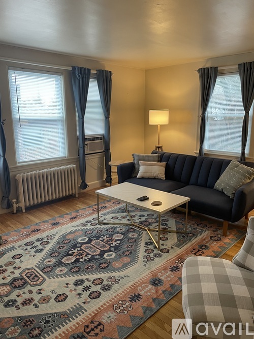 A living room with a blue sofa, a rug, and a coffee table.