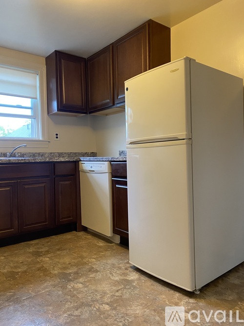 A white refrigerator in a kitchen with brown cabinets.