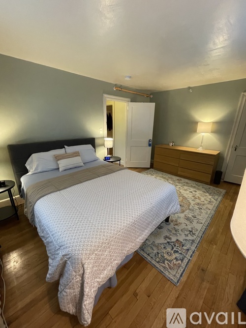 A bedroom with a large bed and a wooden floor.