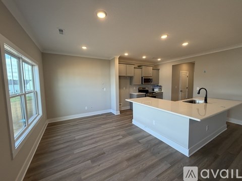A spacious kitchen with a white countertop and wooden flooring.