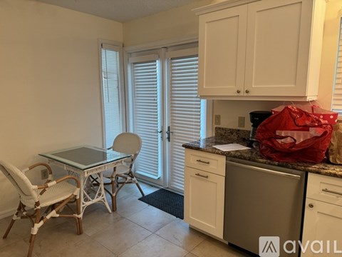A kitchen with white cabinets and a glass table.
