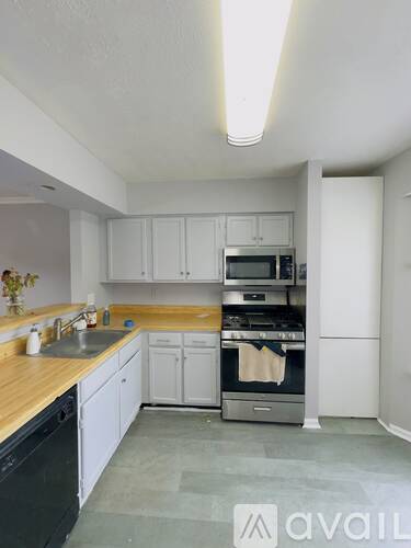 A kitchen with white cabinets and a wooden counter top.