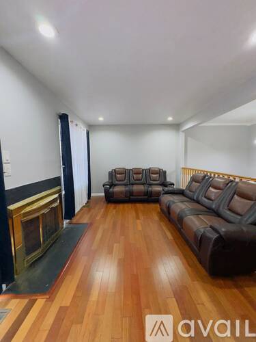 A living room with a brown leather couch and a fireplace.