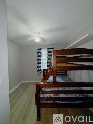 A bedroom with a bunk bed and a window with curtains.