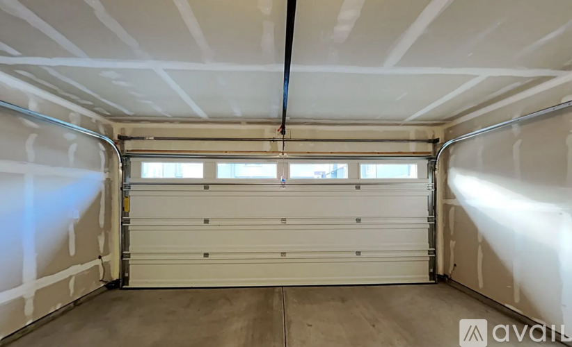 A spacious garage with a white roll-up door and a window.