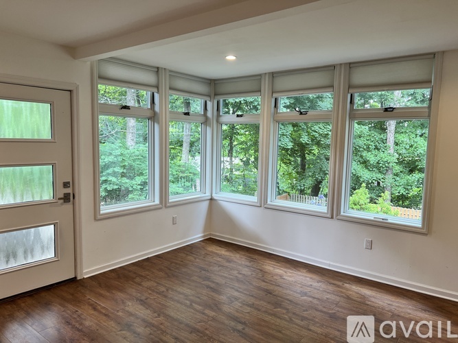 A room with a white door and four windows with a view of trees.