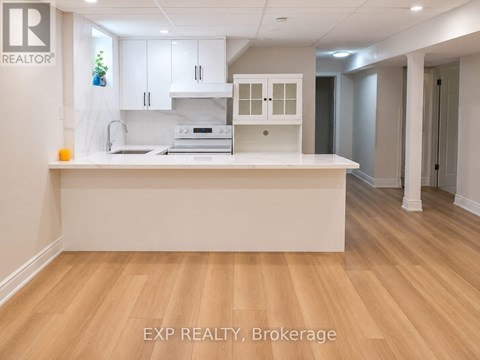 A kitchen with white cabinets and a wooden floor.