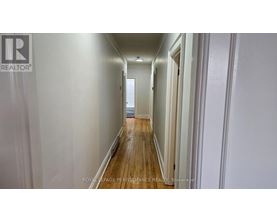 A long hallway with white walls and wood floors.