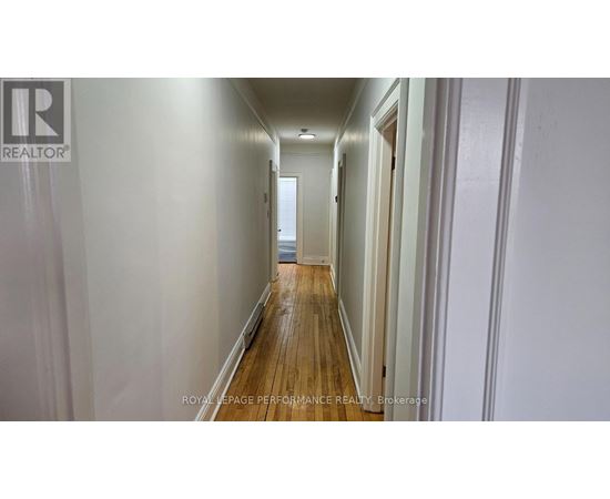 A long hallway with white walls and wood floors.