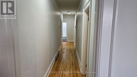 A long hallway with white walls and wood floors.