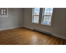 A room with wooden floors and a window showing a view of a building.